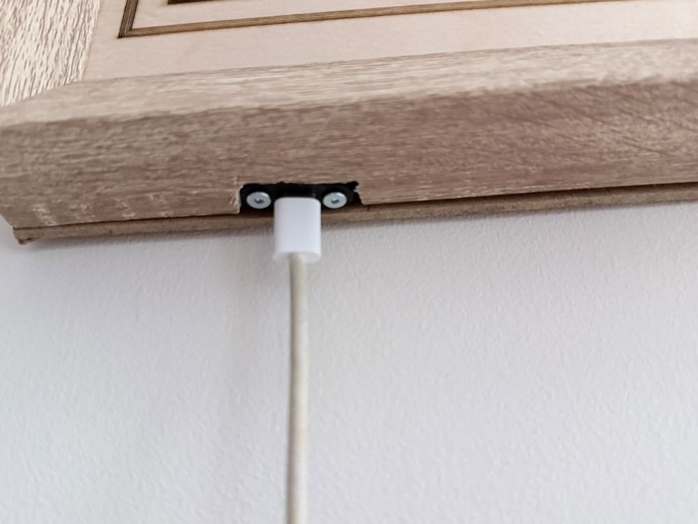 A white USB-C cable plugged into a socket in the bottom edge of the wooden frame